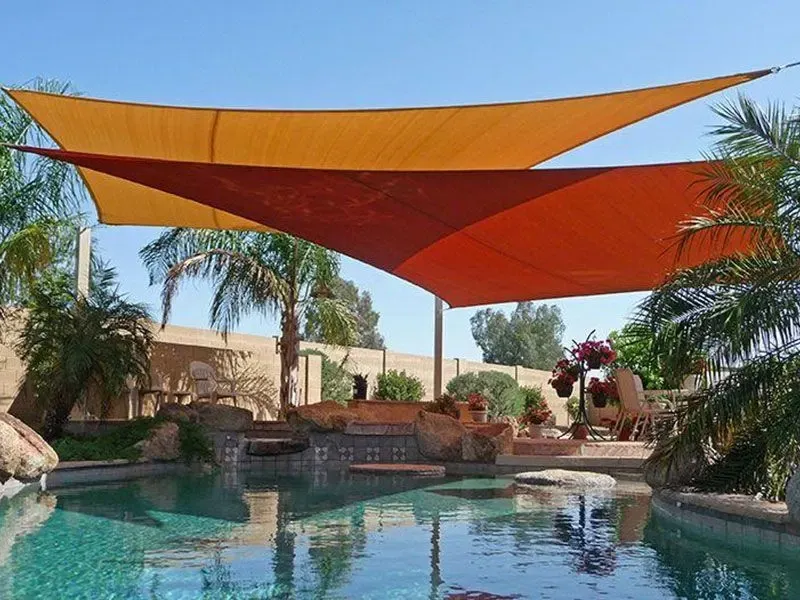 A swimming pool with a red and yellow umbrella over it