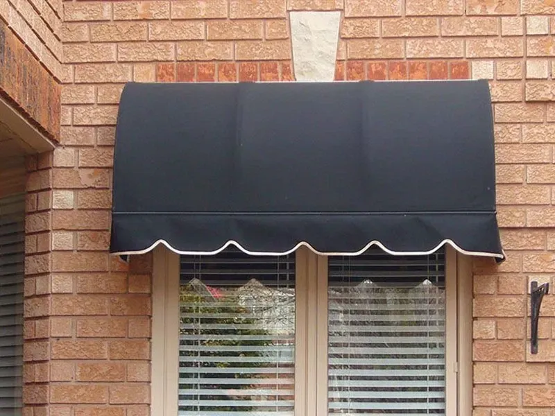 A black awning is hanging over a window on a brick building