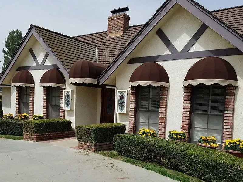 A white house with brown awnings on the windows